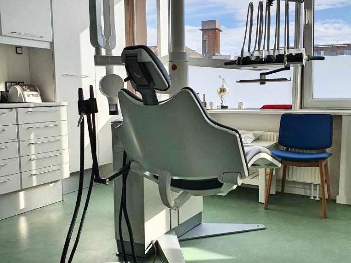 Tandlægestol med forskelligt udstyr og vinduer med folie for neden. Der står også en stol. 