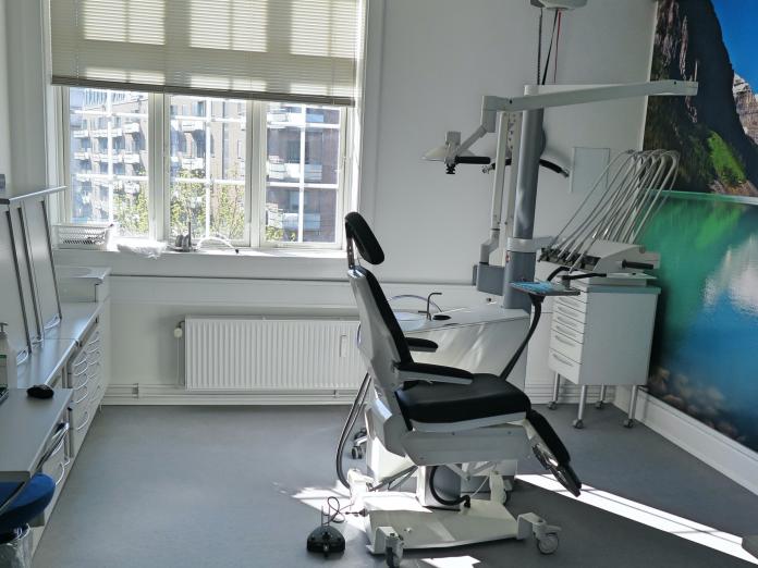 Klinik med tandlægestol med forskelligt udstyr og vægtapet med bjergsø.